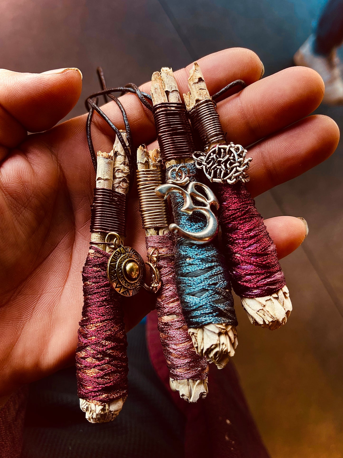 A Handful of sage necklaces with pendants, natural handmade jewelry necklaces of mini sage bundles wrapped in different colors of string, with pendants wire wrapped onto the white sage, beautiful natural necklaces made by Paul Adrian Moon